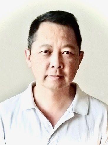 A man in a white shirt is looking at the camera.