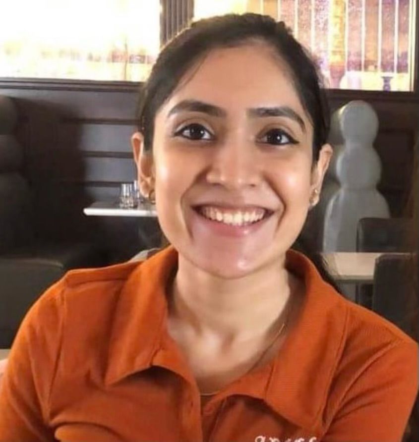 A woman in an orange shirt is smiling for the camera