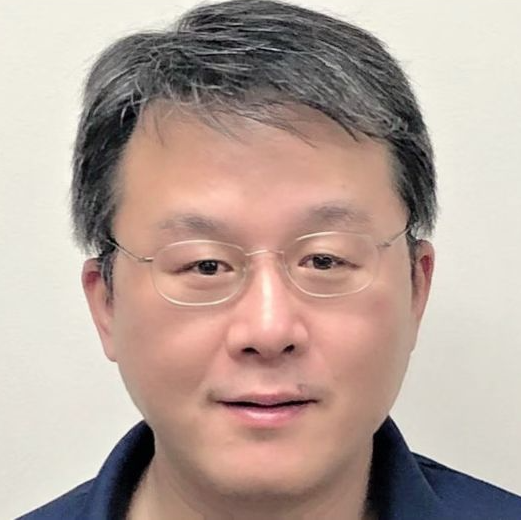A close up of a man wearing glasses and a blue shirt.