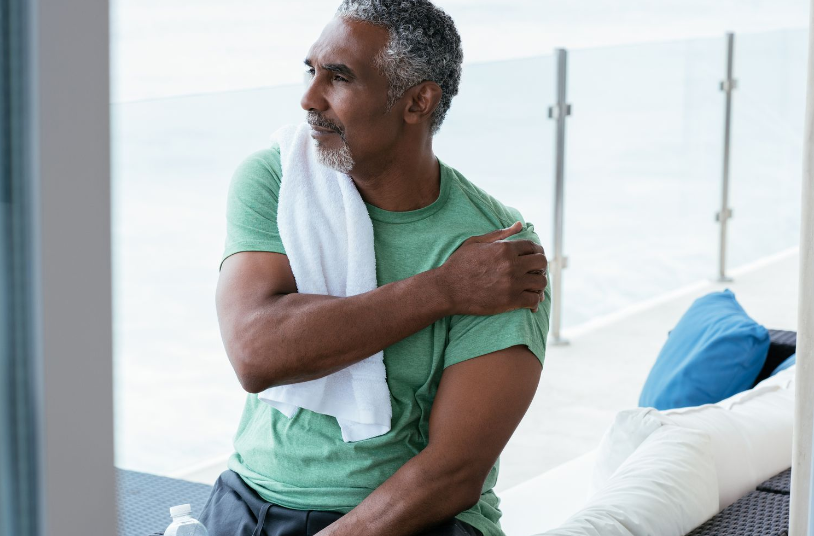 A man is sitting on a couch with a towel around his shoulder.