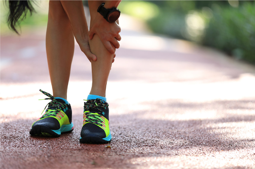 A person is holding their leg in pain while running.