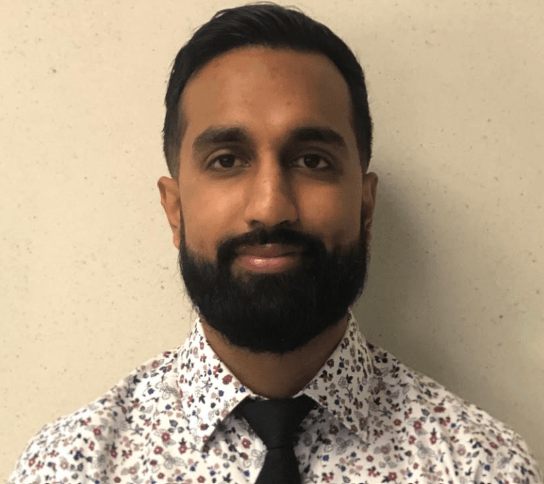 A man with a beard is wearing a floral shirt and tie