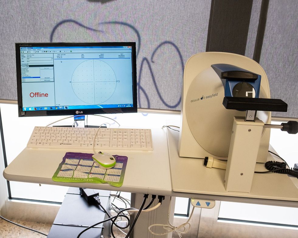 Un dispositivo optometrico perimetrale con monitor, tastiera e mouse su un tavolo da lavoro.