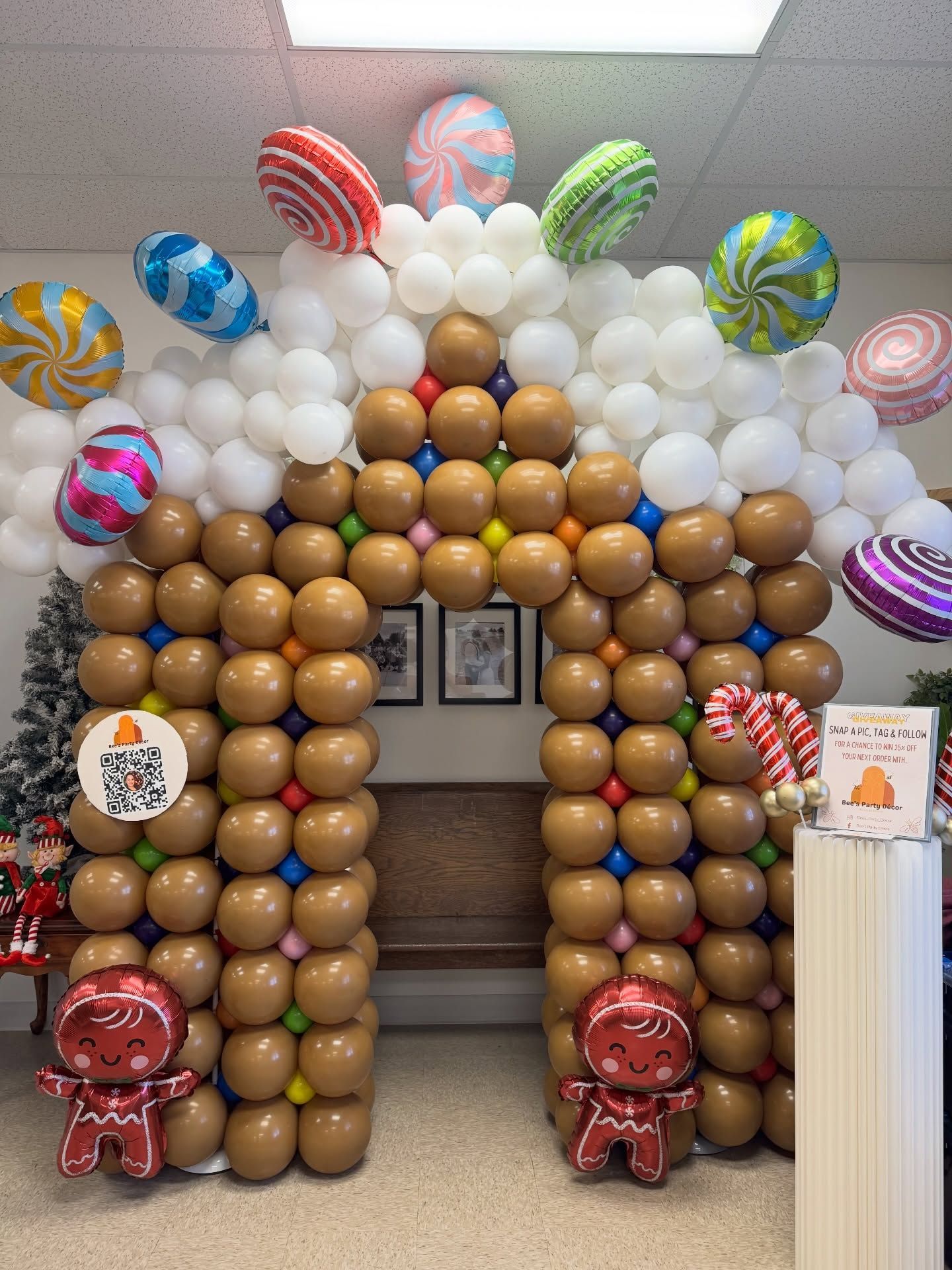 Balloon arch shaped like a gingerbread house with festive holiday balloons and decorations