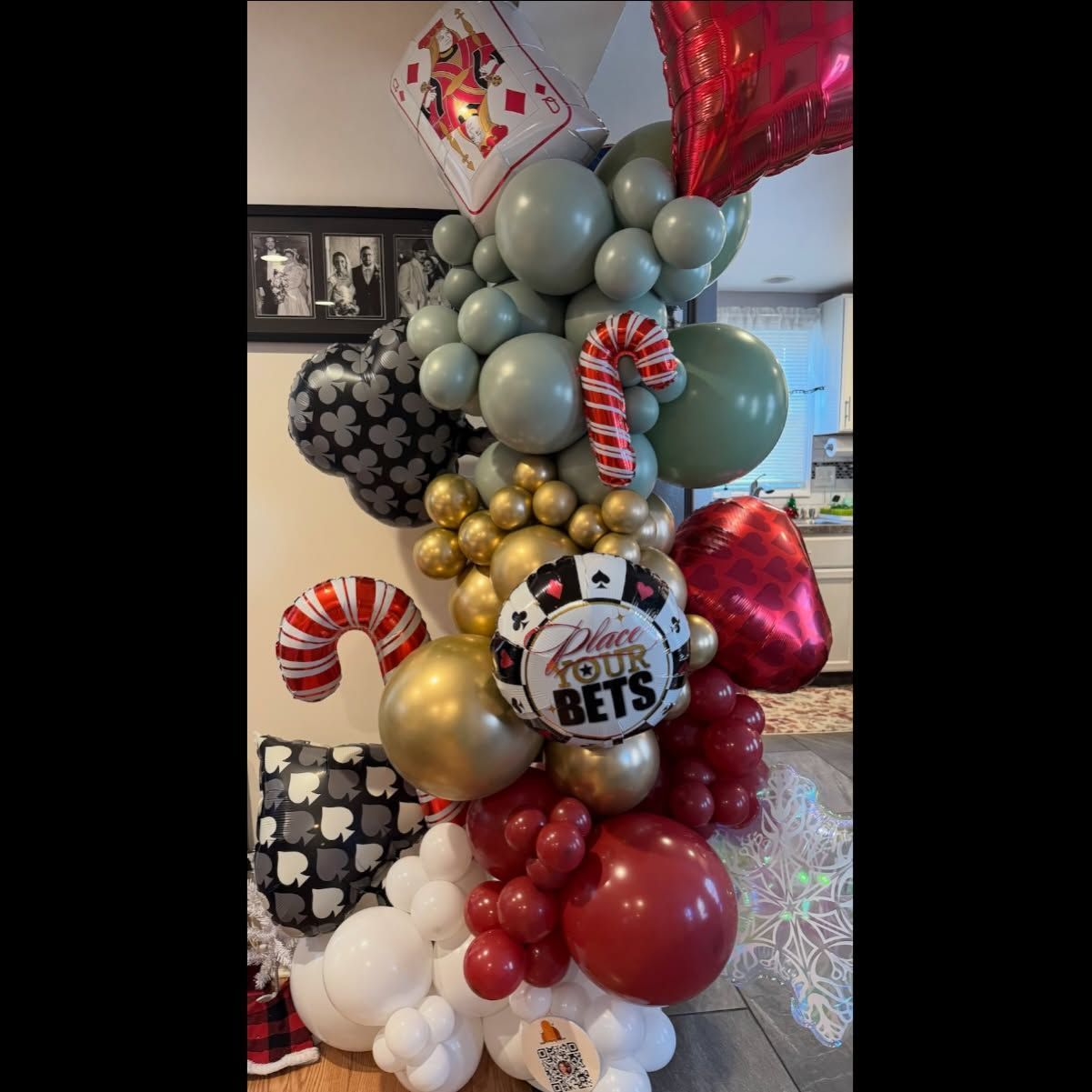 Football-themed balloon column in gray, red, gold, and white with candy cane accents and a “Go Bets” sign