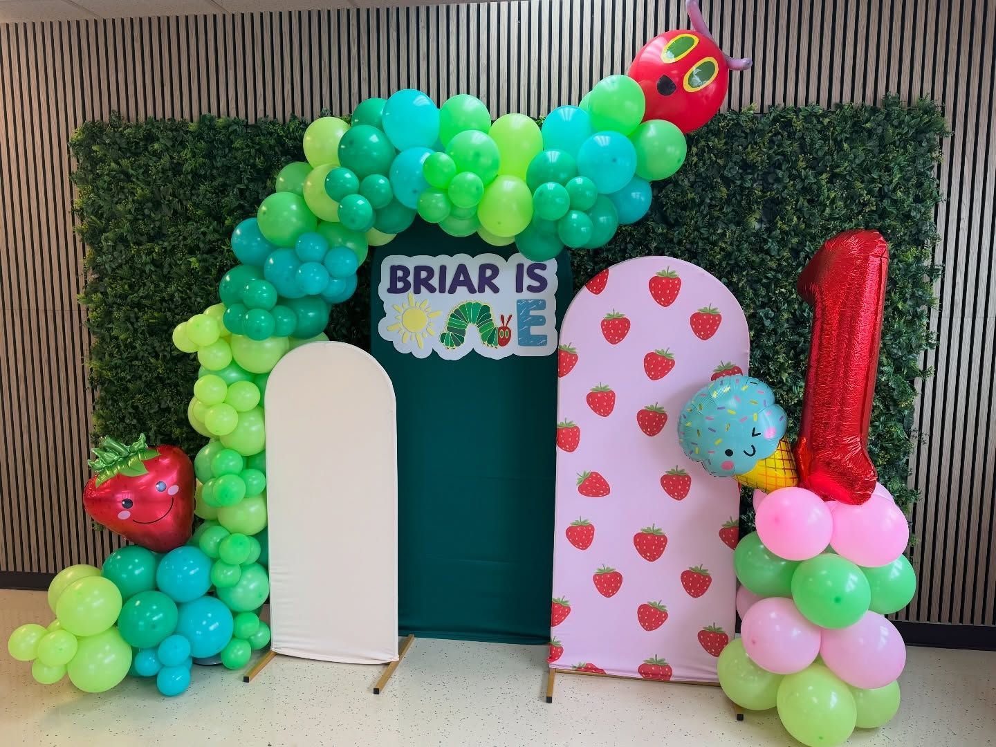 Birthday display with green balloon arch, teal backdrop, and number balloons 8 and 1