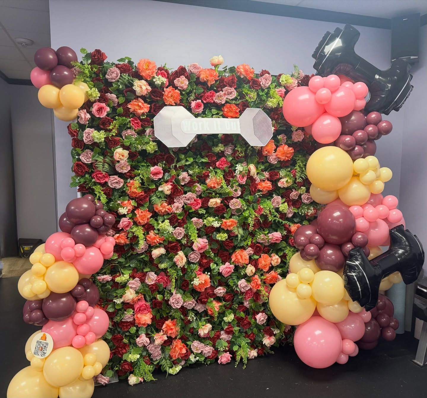 Floral photo backdrop with pink, yellow, and burgundy balloons framing the sides and corners