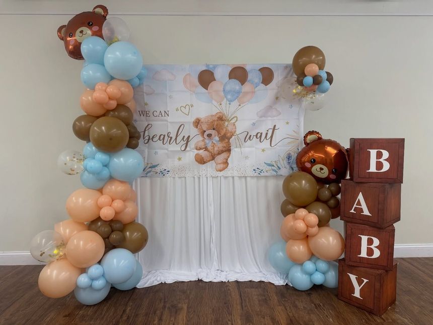 Baby shower backdrop with pastel balloon columns, teddy bears, and stacked BABY blocks