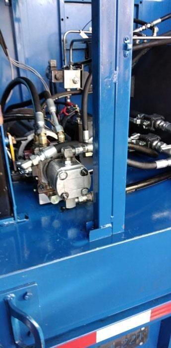 Un primer plano de una máquina azul con mangueras hidráulicas.