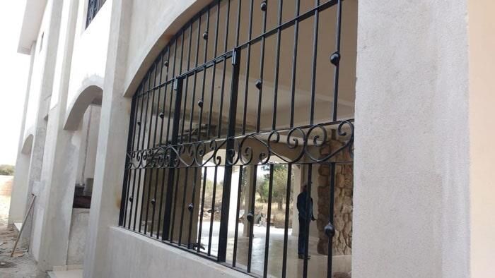 Una valla de hierro forjado está en el costado de un edificio.
