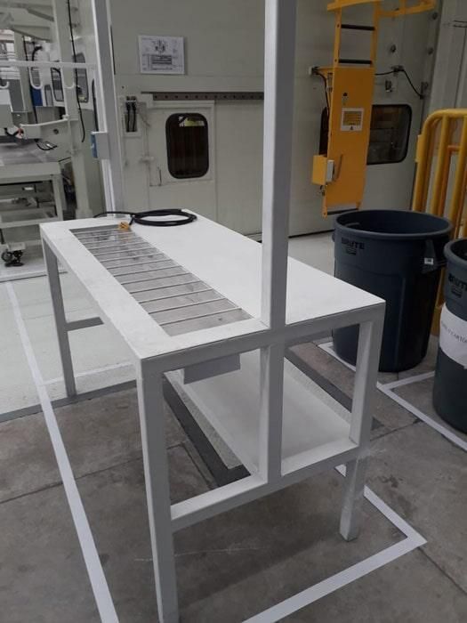 Una mesa blanca en una fábrica con una cinta transportadora sobre ella.