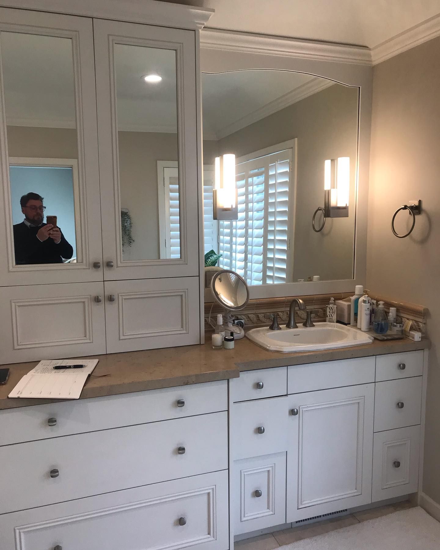 A bathroom vanity with white cabinets, a light-colored countertop