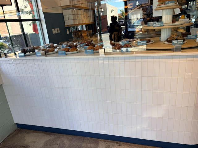 Bakery counter with pastries and display case behind a white tiled front panel