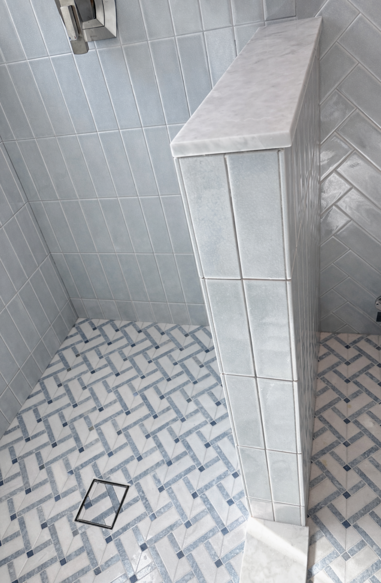Tiled shower corner with a white built-in bench and gray-white mosaic floor