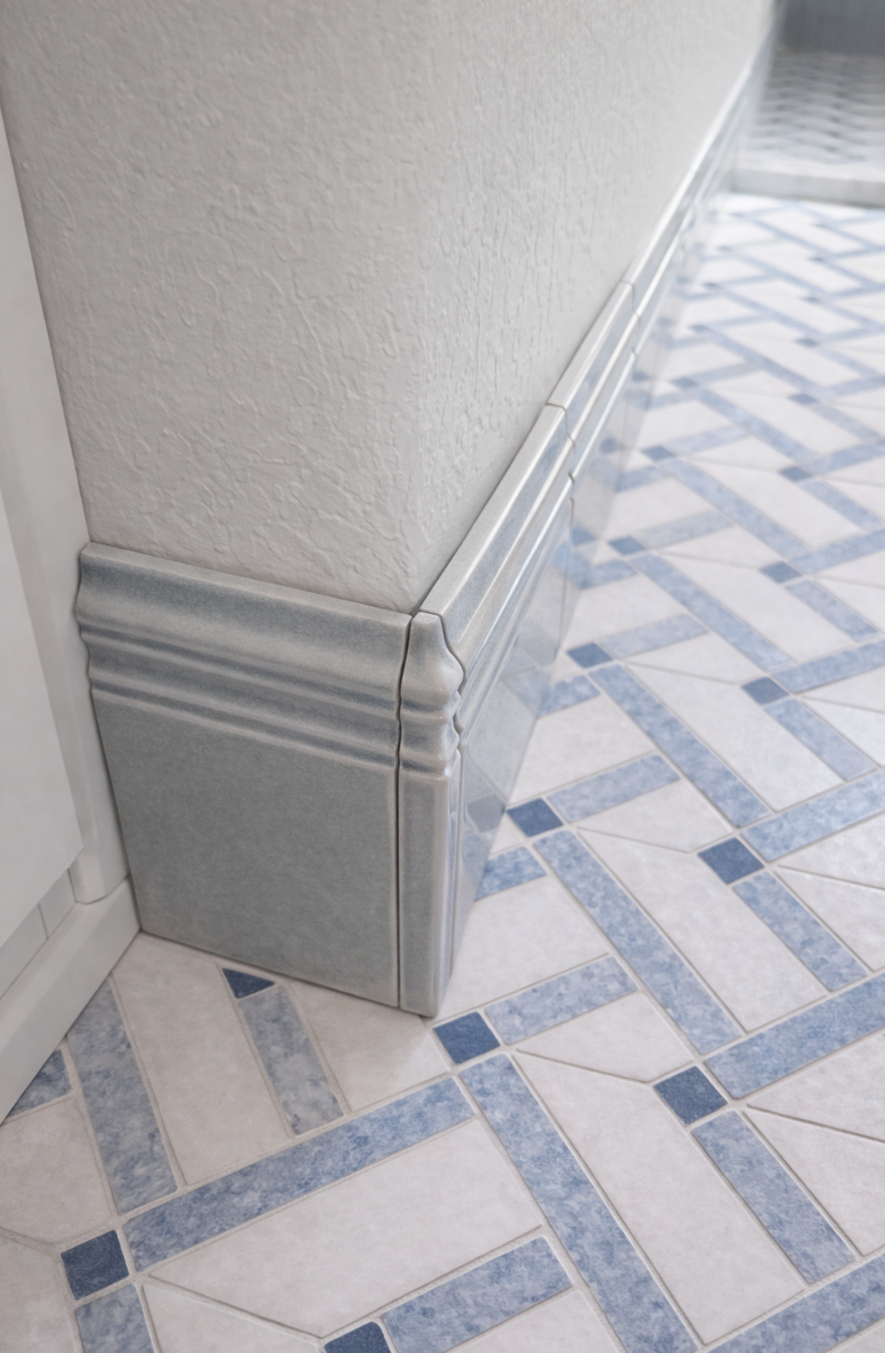 Hallway corner with gray baseboard trim and blue-and-white patterned tile floor.
