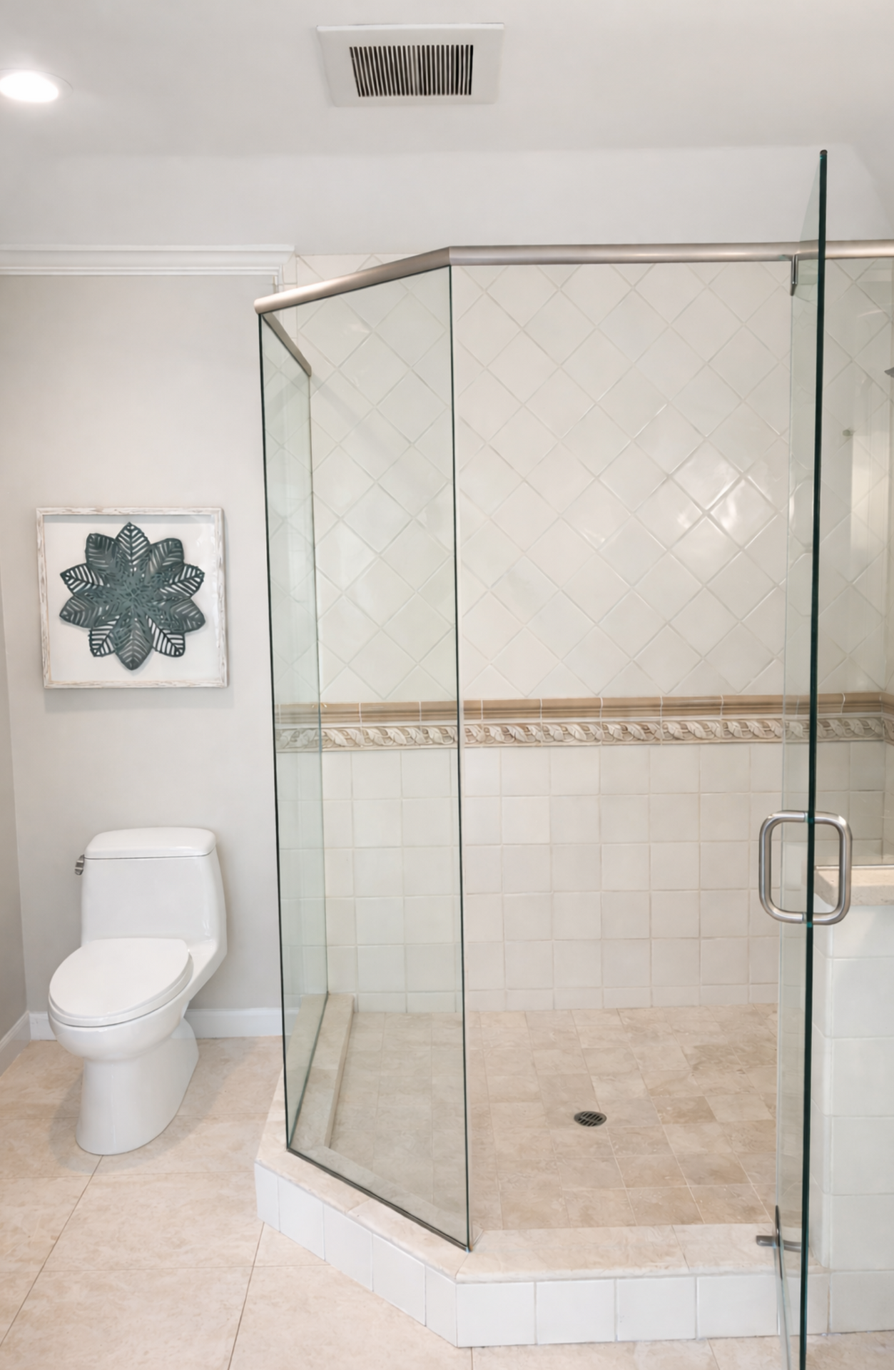 Modern bathroom with glass corner shower, white toilet, and beige tile floor