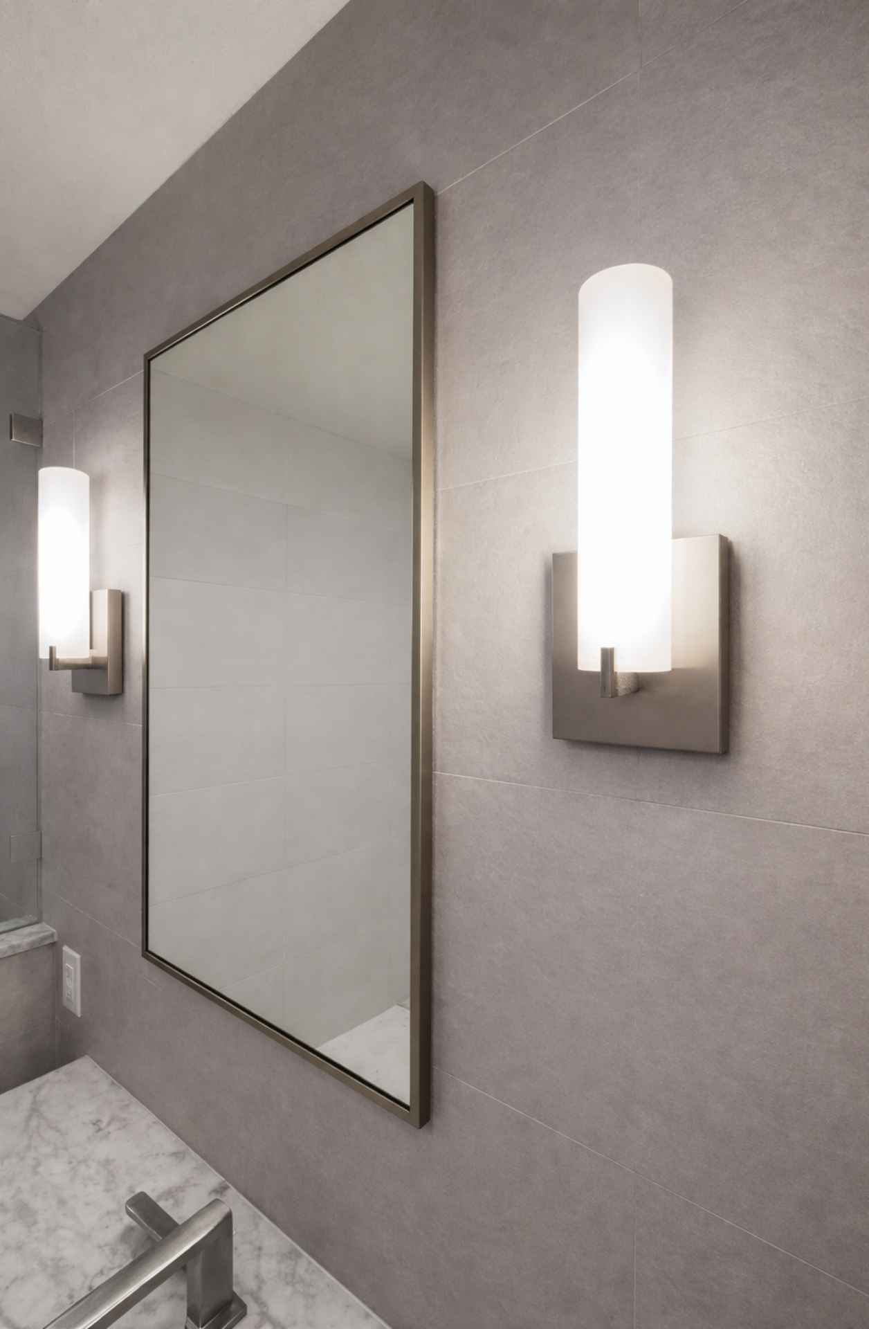 Bathroom wall with large mirror and two wall sconces on a gray textured surface.