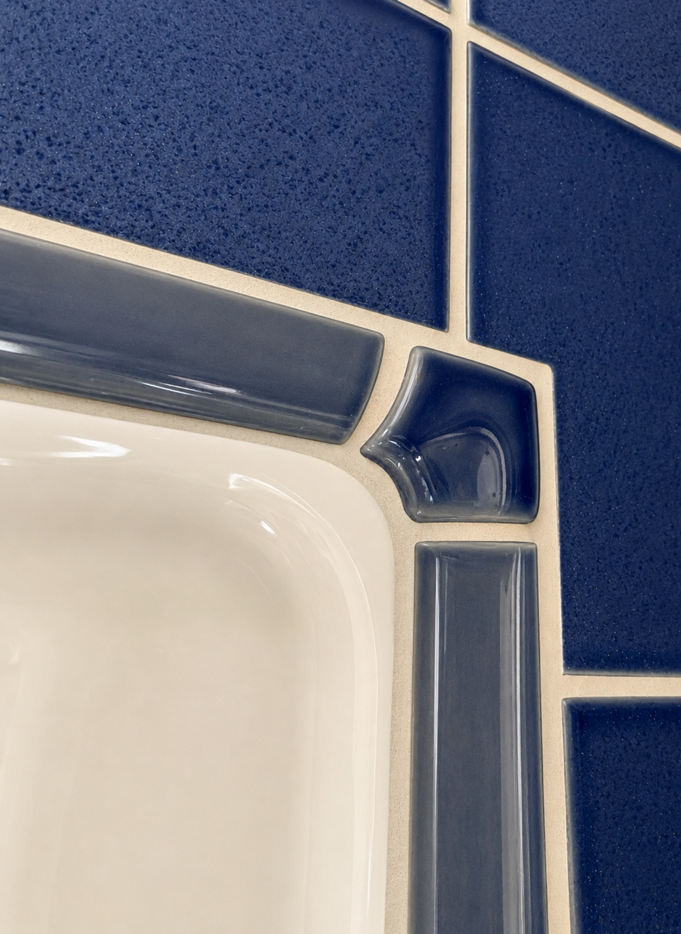 Close-up of a white sink corner with blue-and-white tiled wall behind it