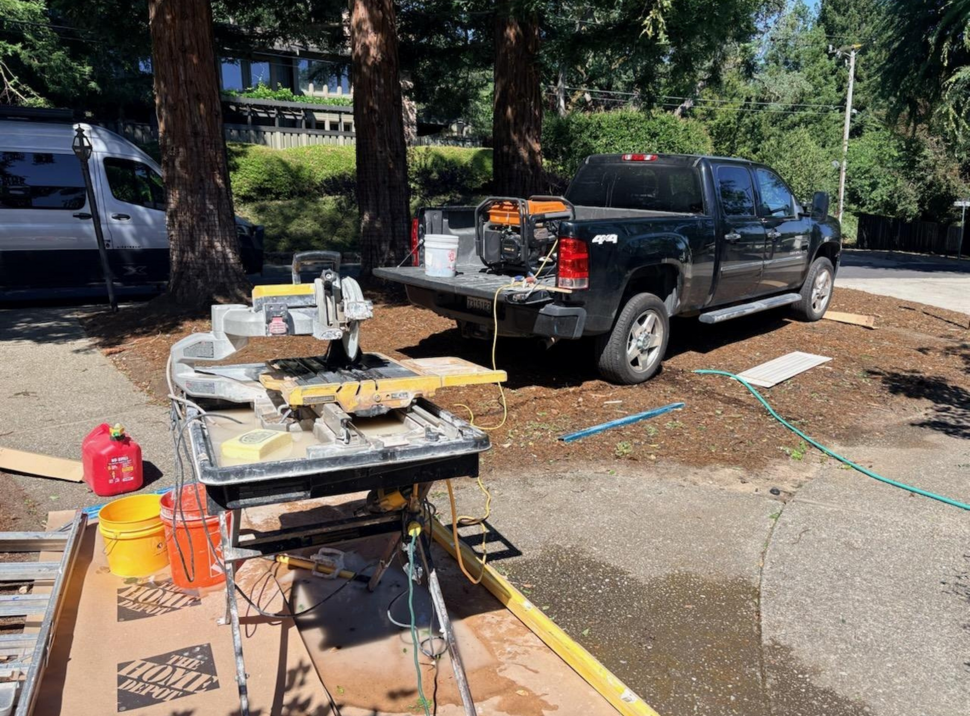 Construction tools and materials on a workbench beside a black pickup truck in a sunny outdoor lot