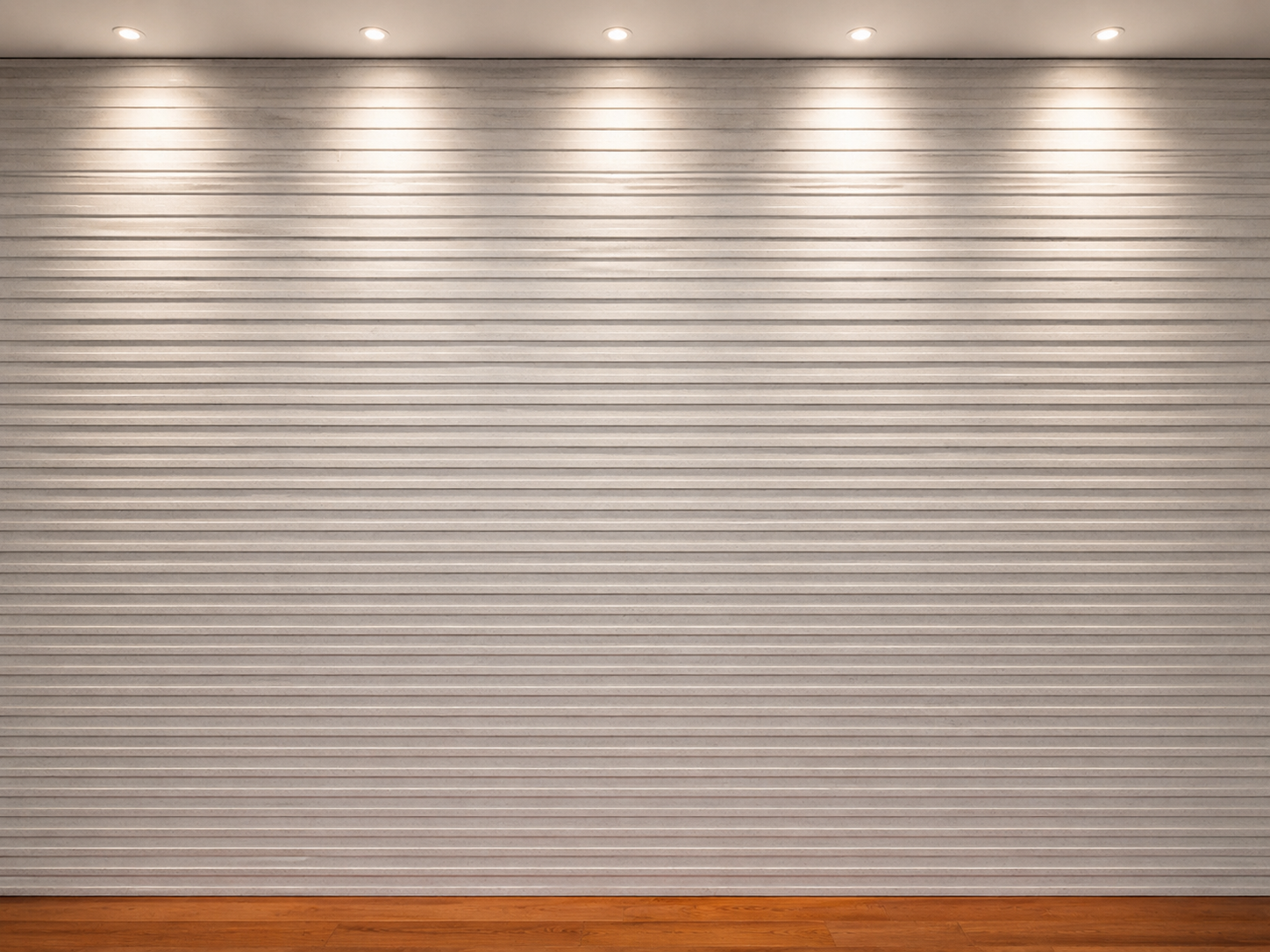 White paneled wall with three spotlights above a wooden floor