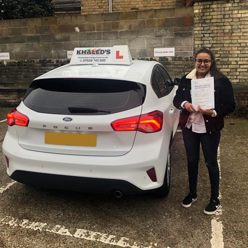Young woman holding certificate next to car