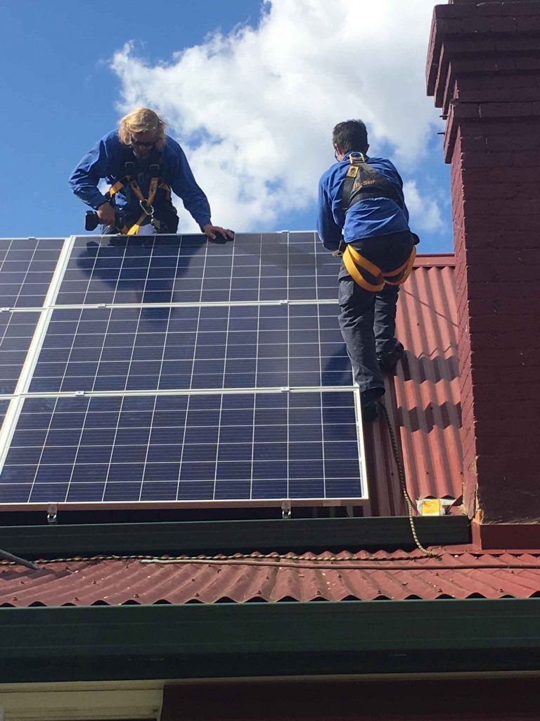 Two Men Are Installing Solar Panels on the Roof of a House — Sapphire City Solar & Electrical In Inverell, NSW
