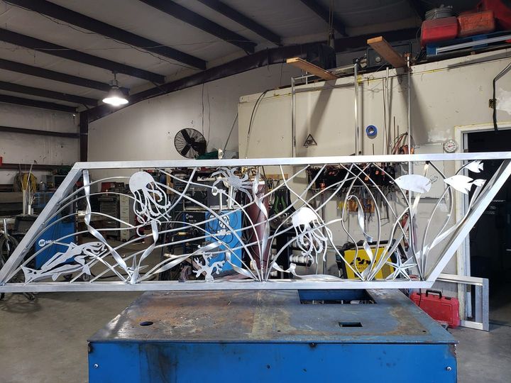 Large mechanical apparatus with tangled wires in a workshop or lab, behind a blue workbench