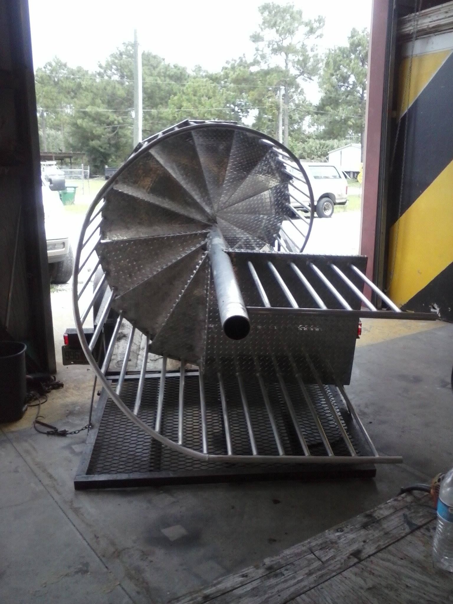 Industrial spiral metal machine with grated ramp at an open garage bay