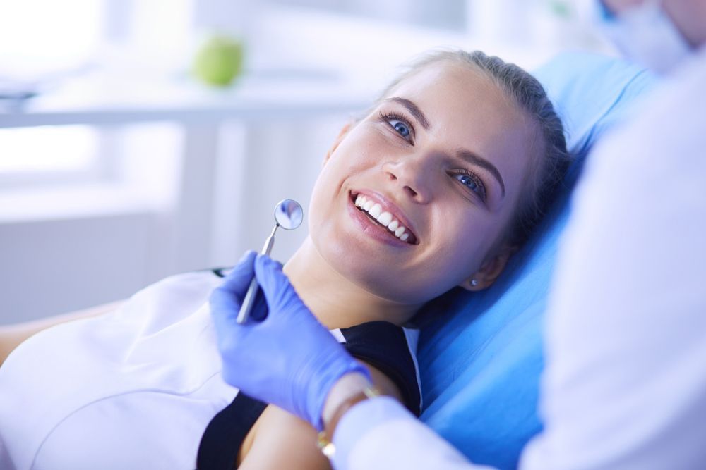 A woman is smiling while having her teeth examined by a dentist.