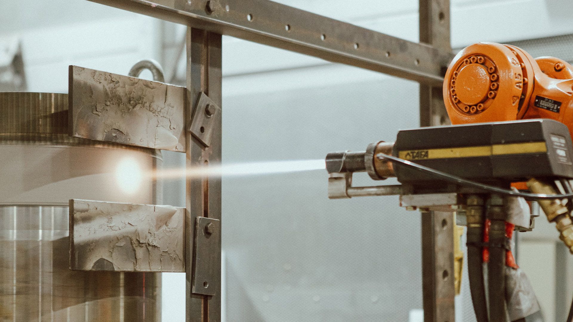 A machine is spraying a liquid on a metal object at New Metal Surfaces factory.