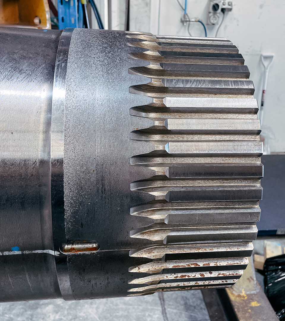 A large metal gear rests on a table, awaiting in-house repair at New Metal Surfaces.