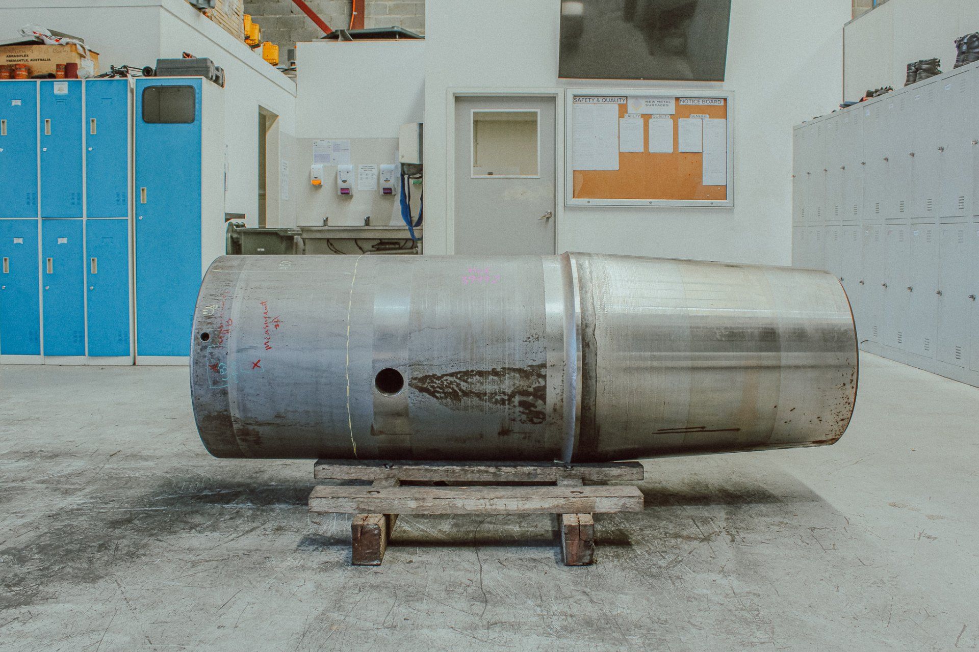A secondary cone crusher is sitting on a wooden the pallet in New Metal Surfaces warehouse.