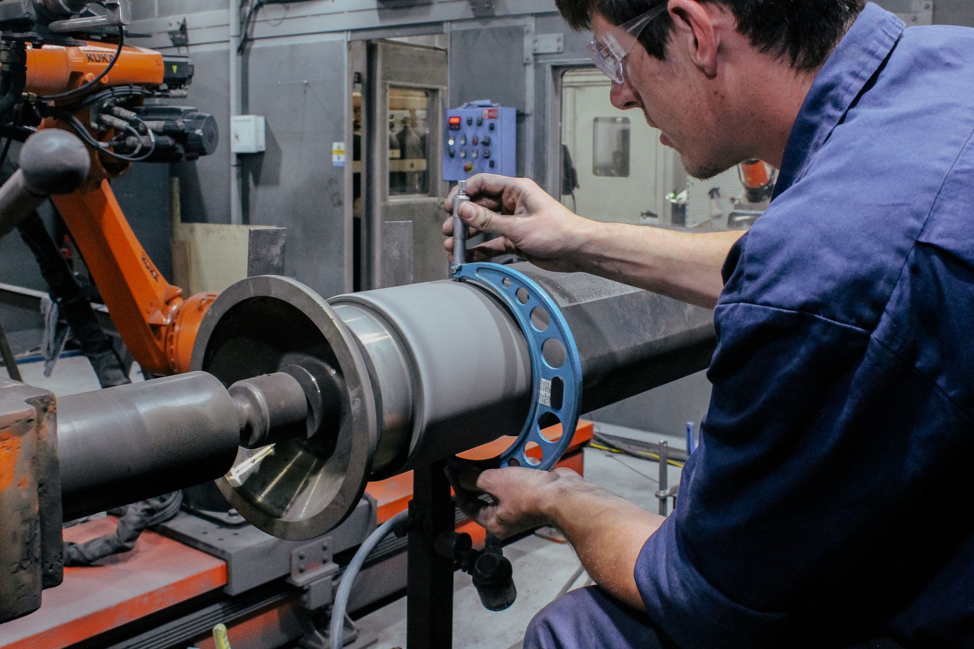 A man is measuring a piece of metal at New Metal Surfaces factory.