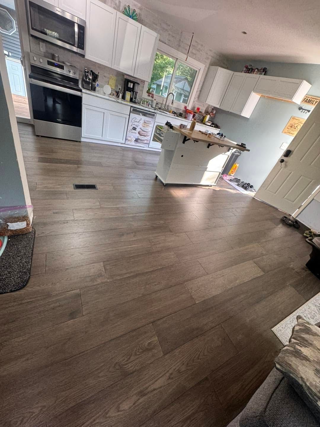 Bright kitchen with wood floors, white cabinets, island, and a view of the entryway.