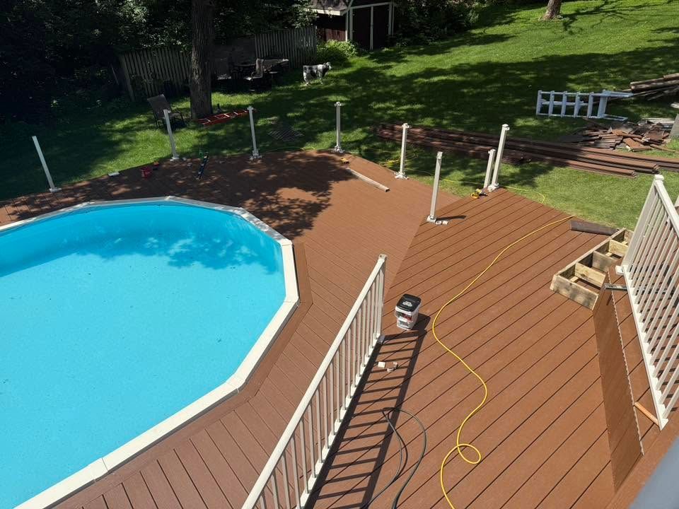 Backyard deck beside a blue pool, with lounge chairs and a hose on the wooden surface.