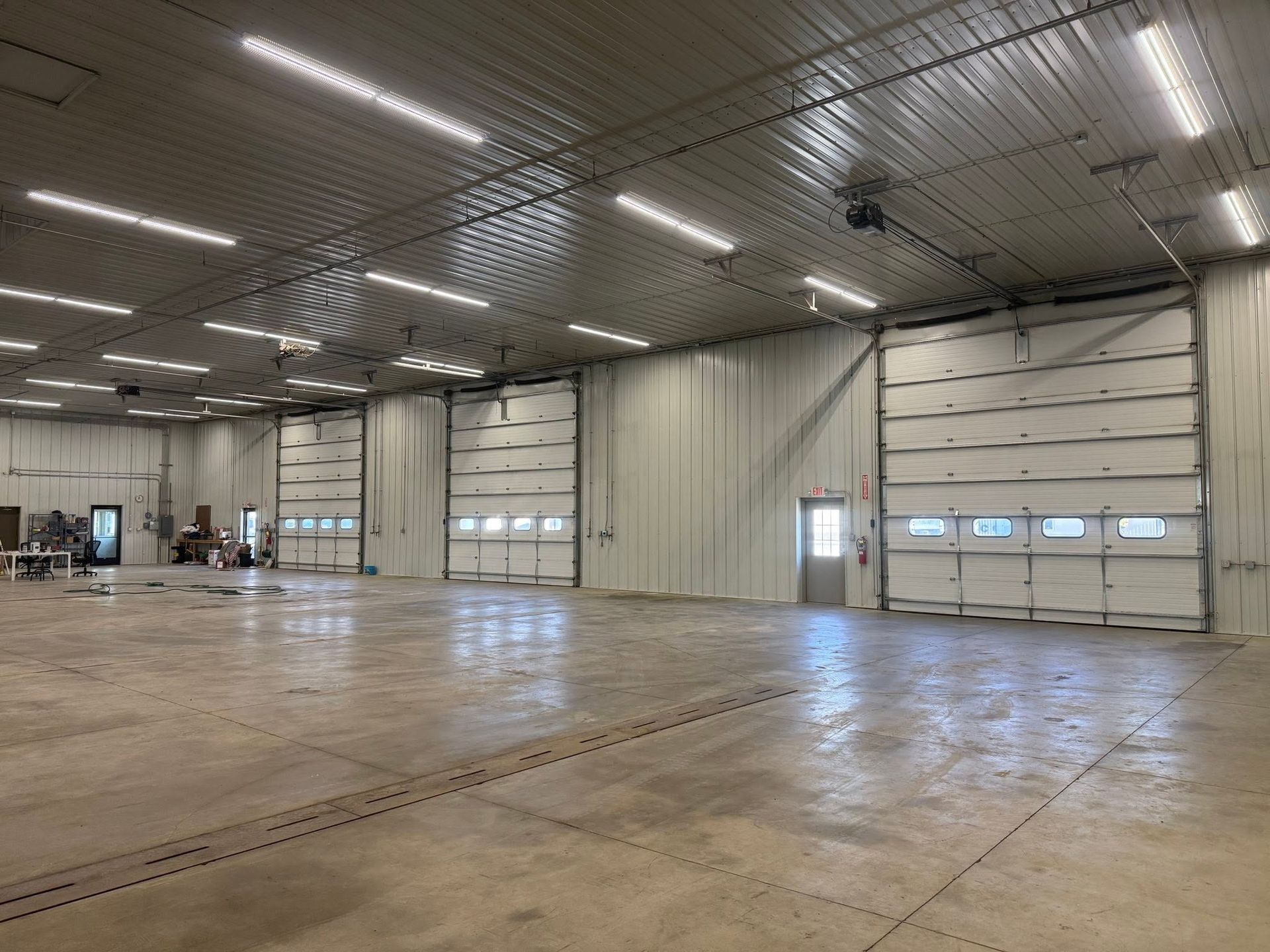 Empty industrial warehouse interior with large roll-up doors and a polished concrete floor