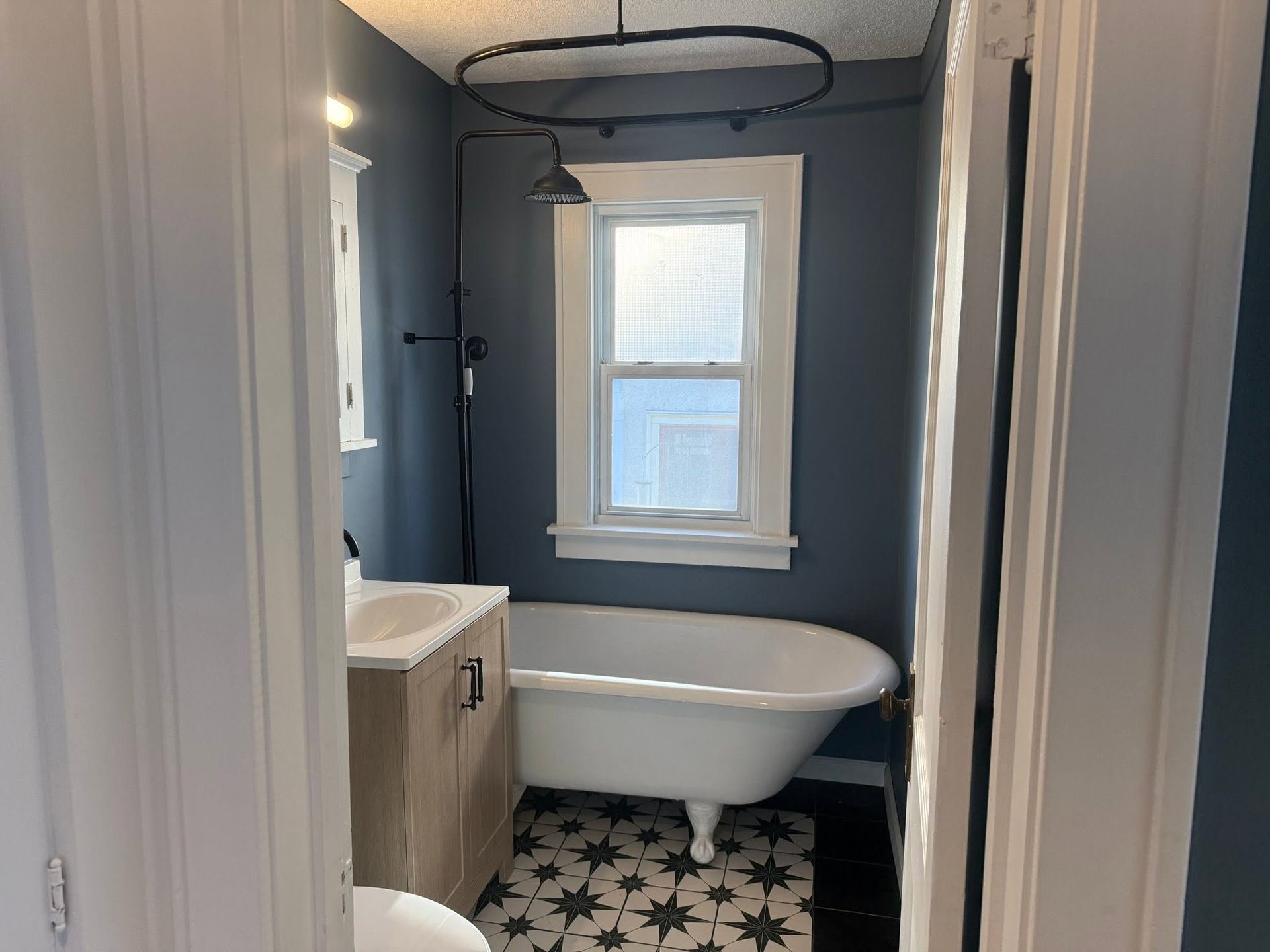 Small bathroom with a clawfoot tub, window, and black-and-white tile floor