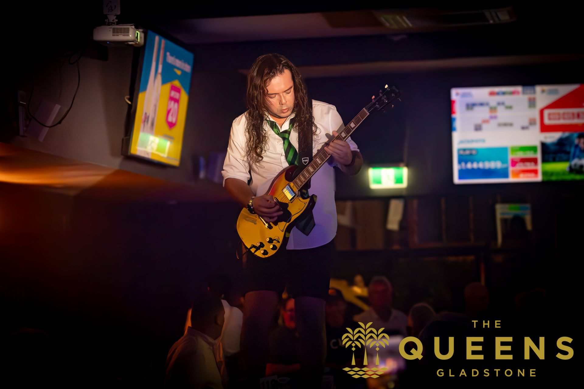 Guitarist performing onstage under purple lights at The Queens, Gladstone