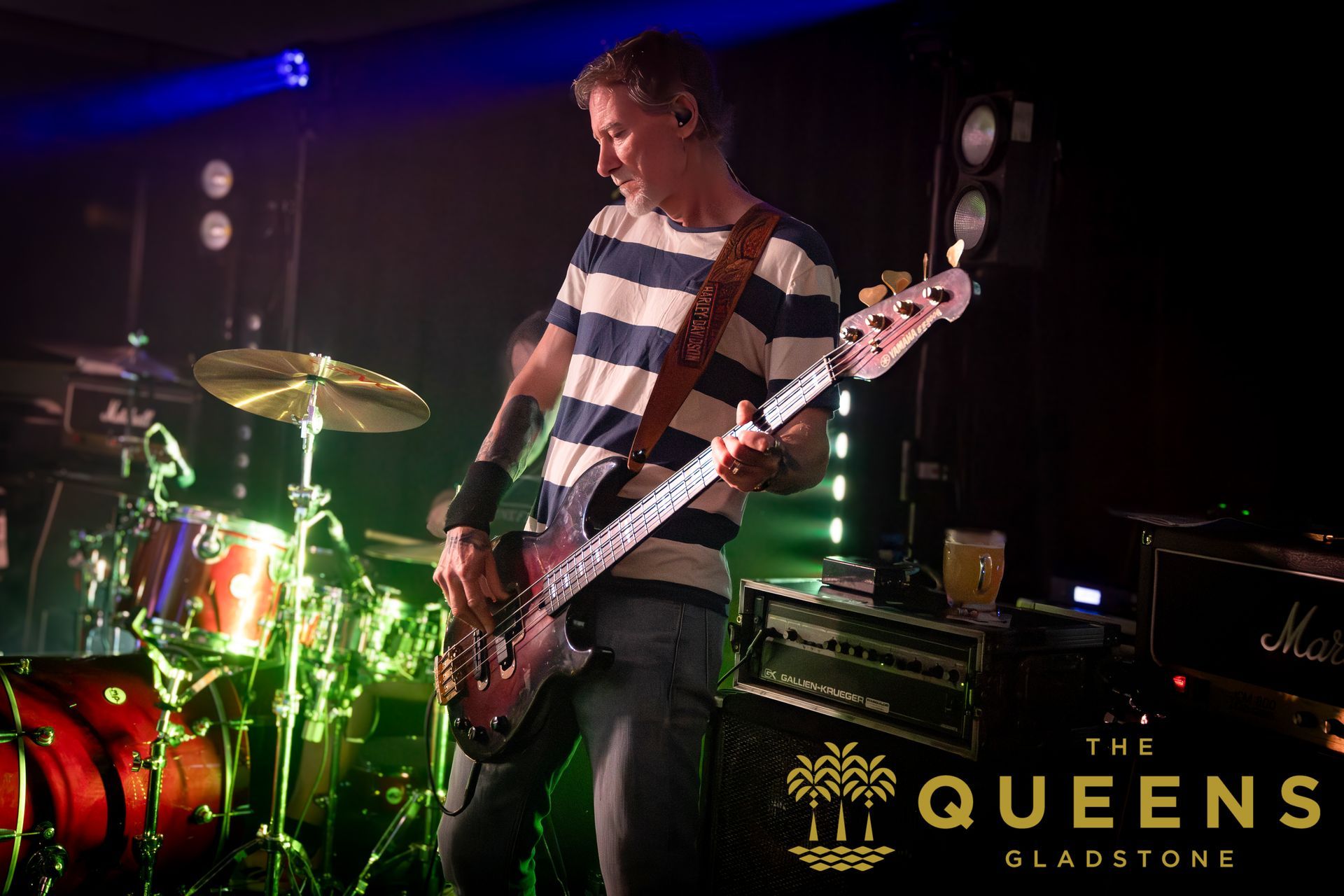 Musician playing bass onstage under colored lights at The Queens, Glasgow