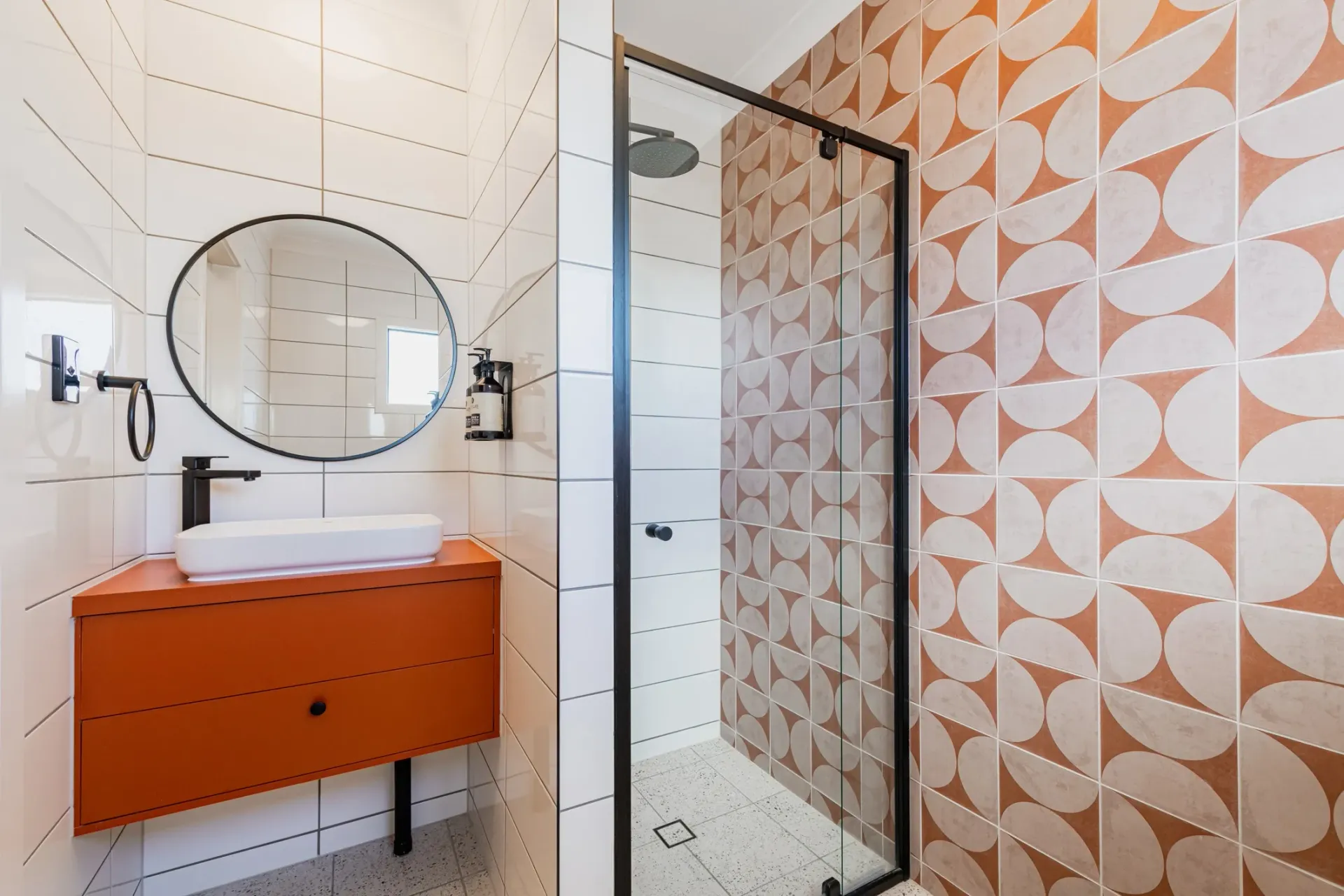 A bathroom with a sink , mirror and shower.