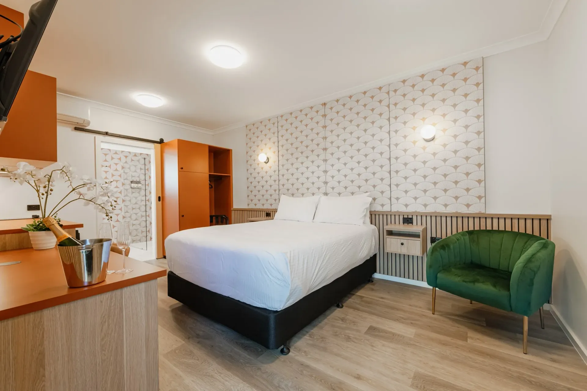 A hotel room with a king size bed and a green chair.