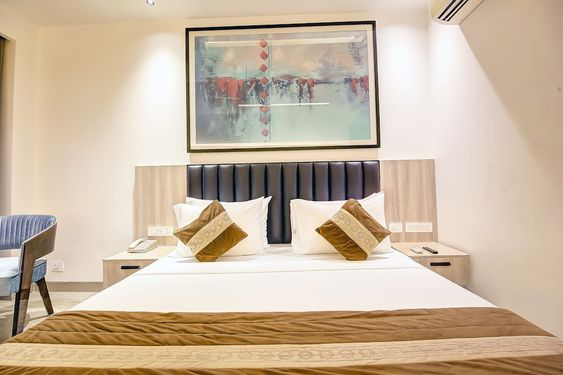 A hotel room with a king size bed and a painting on the wall.