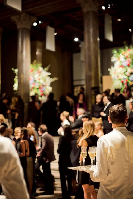 A man is holding a tray of wine glasses in front of a crowd of people