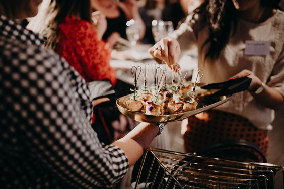 A woman is serving food to a group of people at a party.