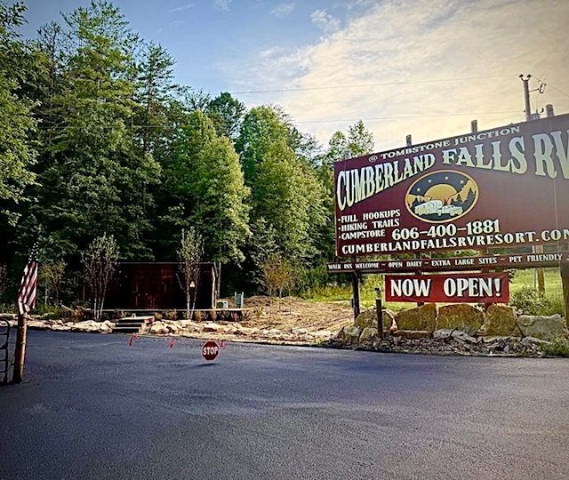 Cumberland Falls RV Resort entrance with a sign, open road, and trees.