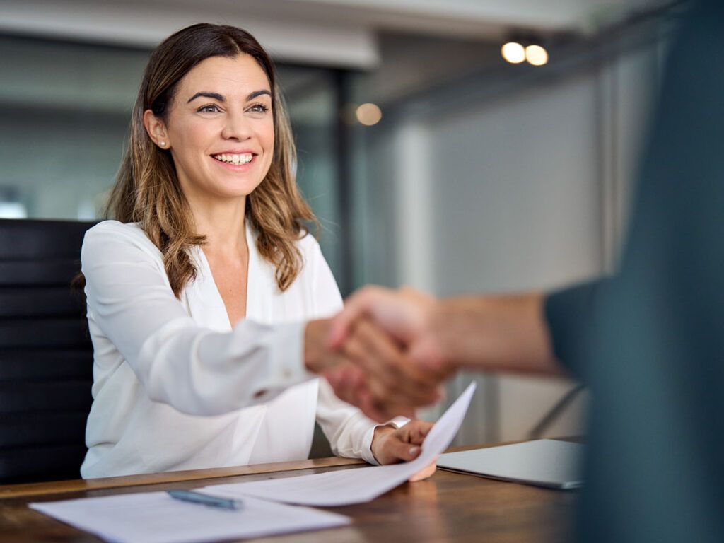 A woman is shaking hands with a man at a table.