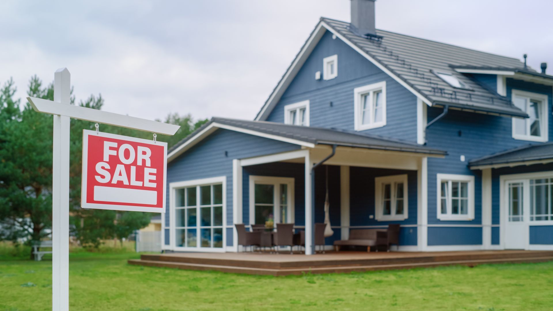 A beautiful blue home with a for sale in the front