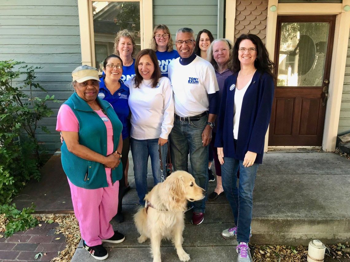Group standing outside a house with a golden retriever in front of the doorway.