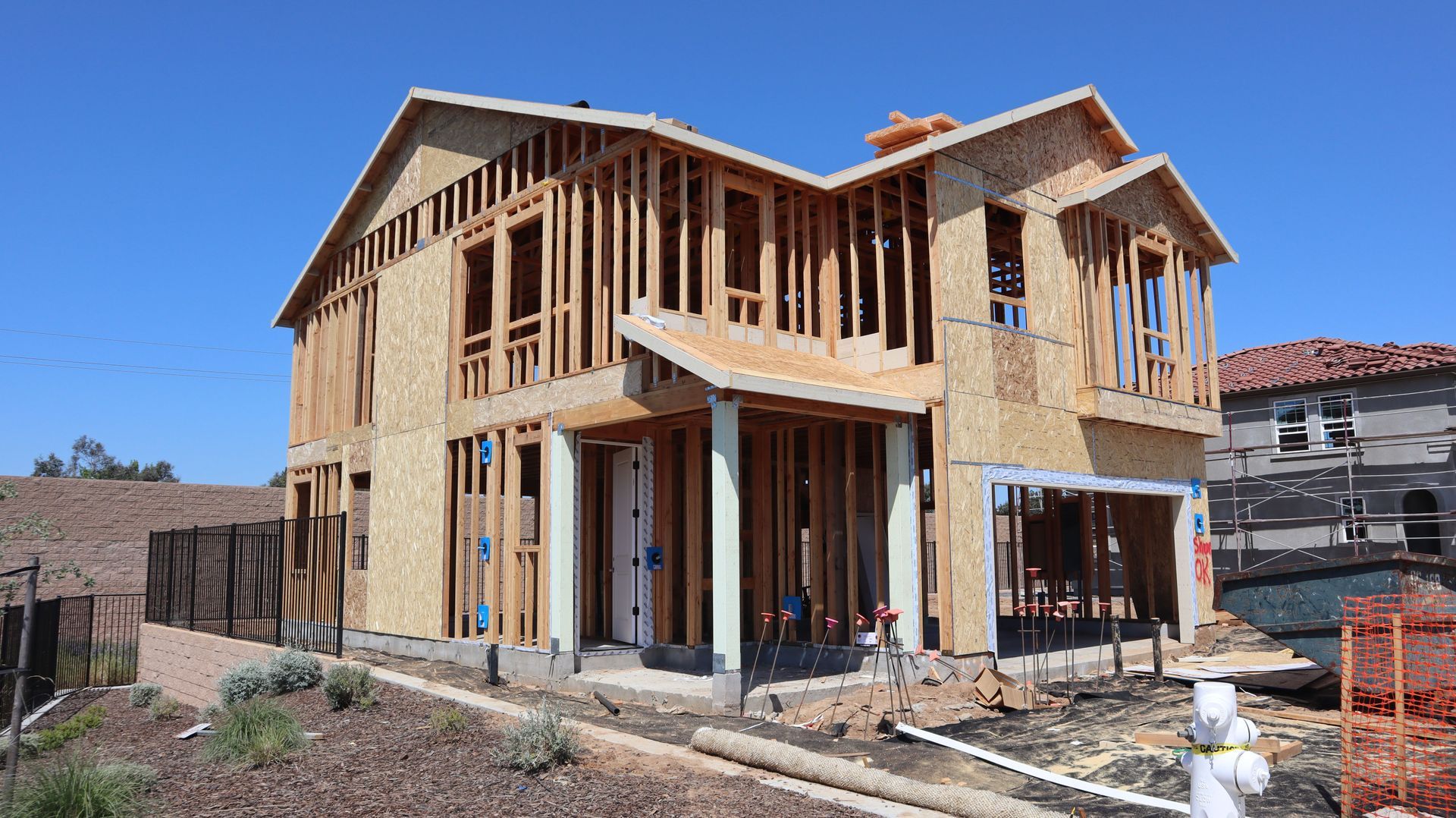 Partially built two-story wooden house under construction on a sunny day