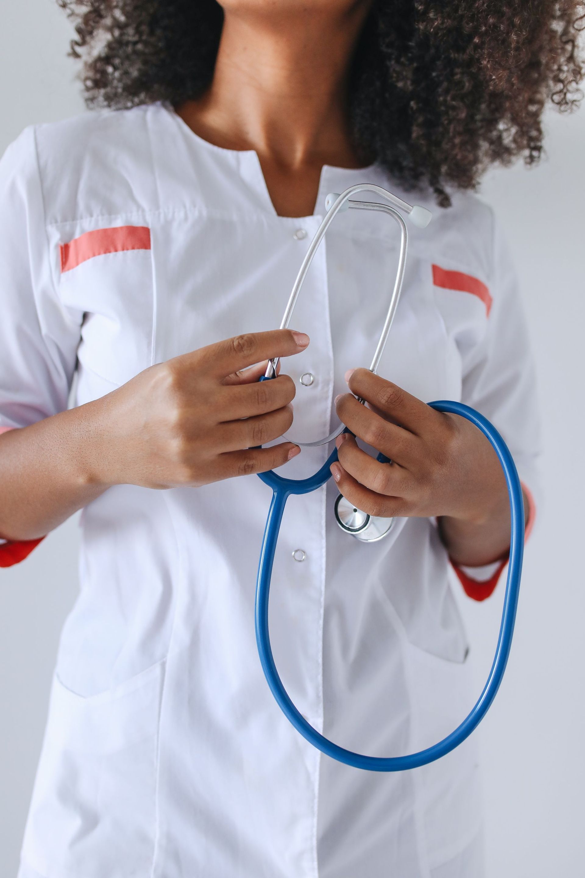 Healthcare worker in white coat holding a blue stethoscope